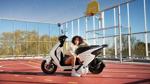 Eine Person sitzt auf einem weißen Honda M1E Roller auf einem Basketballplatz.
